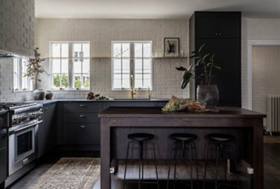 Image of modern kitchen with white brick walls, dark brown bartop, and dark green cabinets.