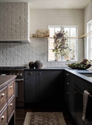 kitchen with dark cabinets and white brick walls and natural light.