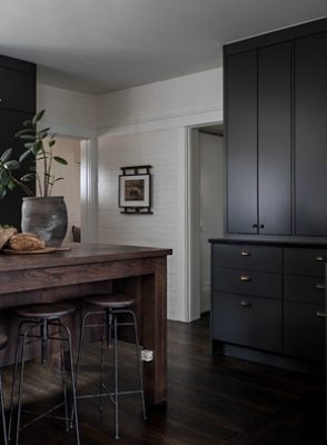 dark kitchen with pantry and bartop stools.