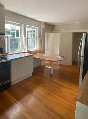 before photo of bland kitchen with white cabinets and wooden accents.