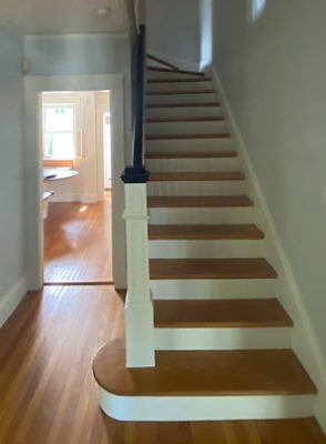 peek into a wooden staircase with white paint on the front facing.