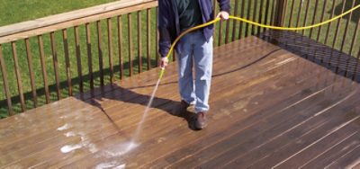 A person cleaning a deck with a water hose