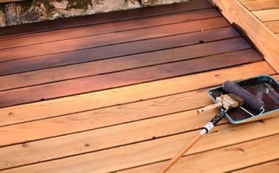 A wood deck getting stained with a roller brush.