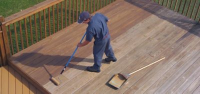 A wood deck getting stained with a roller brush.