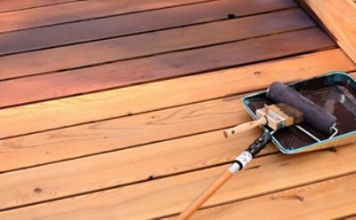 A wood deck getting stained with a roller brush.