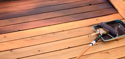 A wood deck getting stained with a roller brush.