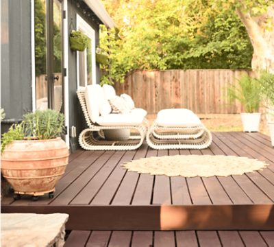 Outdoor patio deck with neutral furniture, rug, and plants.