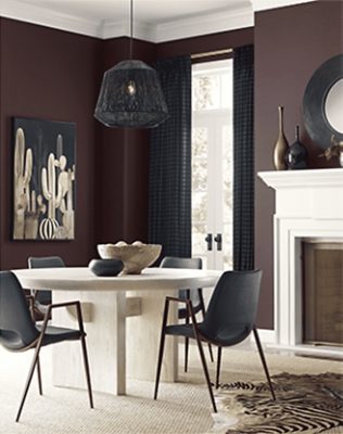 Dark purple walls in a living room with a round table and chairs, fireplace, and decor.