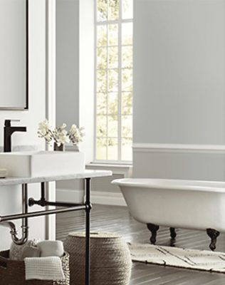 Neutral bright bathroom with large window and baskets for storage.