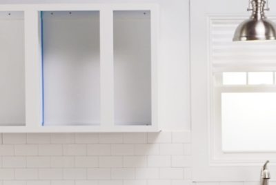 Empty wall cabinets with painter's tape applied, ready for painting.