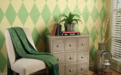 A sitting area with earth-toned diamond pattern wall and a chair with a throw on top.