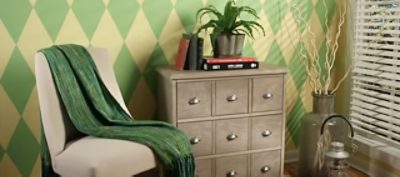 A sitting area with earth-toned diamond pattern wall and a chair with a throw on top.