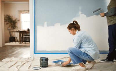 Two people rolling out Sherwin-Williams Emerald white onto a wall.