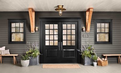 The covered front porch of a home with double entry doors painted black.