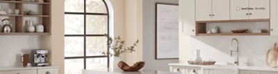 Kitchen walls painted in SW 6099 Sand Dollar with a large window and island.