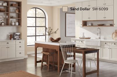 Kitchen walls painted in SW 6099 Sand Dollar with a large window and island.