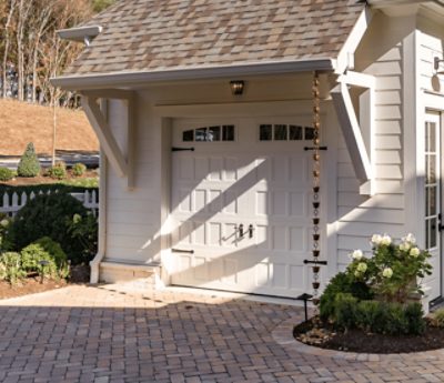 White garage with brick driveway.