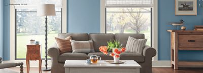 A living room with large windows and wood floors painted in SW 9148 Smoky Azurite. 