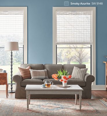 A living room with large windows and wood floors painted in SW 9148 Smoky Azurite. 