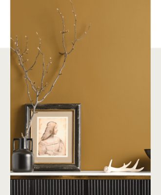 A tabletop with decor in front of a bronze gold wall.