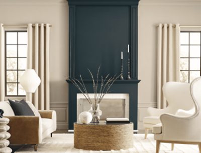 A living room with neutral colored furniture and walls with a greenish gray fireplace.