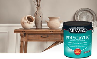 A stained side table holding neutral colored pottery and a can of Minwax stain.