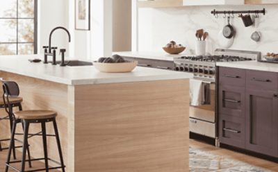 A white kitchen with large pendant lighting over the island that has a natural wood bottom and white countertop.