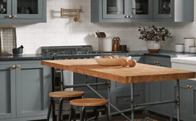Blue-grey cabinets in a kitchen with a wooden table and stools.