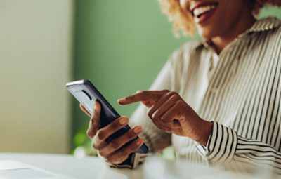 A person smiling while using their smart phone.