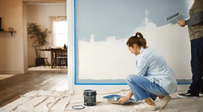 Two people rolling out Sherwin-Williams Emerald white onto a wall.