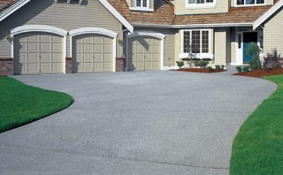 A suburban home with a grey concrete driveway.
