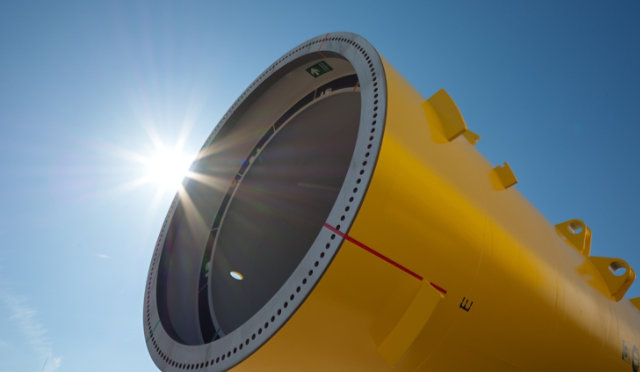 Close up of a yellow monopile with sun shining in background