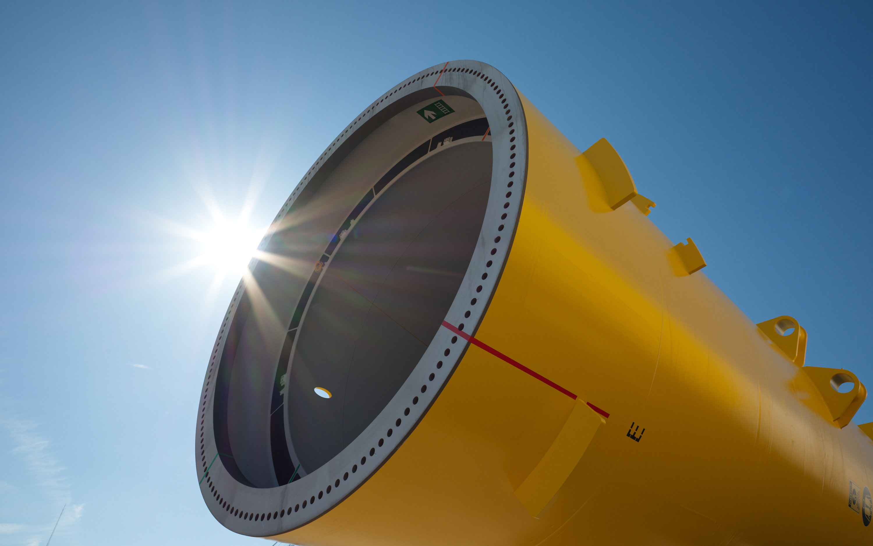 Close up of a yellow monopile with sun shining in background