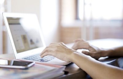 Person Typing on a laptop at a desk.