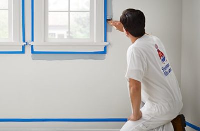 Un pintor profesional colocando cinta de enmascarar para pintura a la moldura de pared.