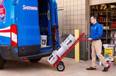Repartidor de Sherwin-Williams cargando botes de pintura en un camión de reparto.