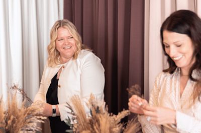 Two people laughing together while arranging dried wheat stalks into bouquets.