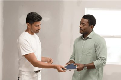 A painter and customer looking at color swatches in a white room.