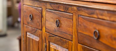 Close-up of a dark-stained wooden dresser, highlighting the rich color and smooth finish of the wood.