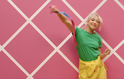 A person dancing in front of a pink wall with a pattern created by using painters tape.