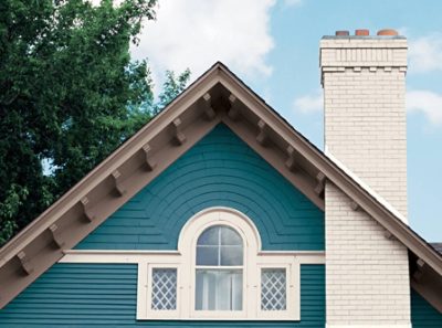 The pitch of a blue exterior house with white trim and chimney.