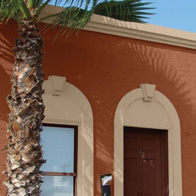 The exterior of a home featuring the architectural style of the home, adjacent to a palm tree.
