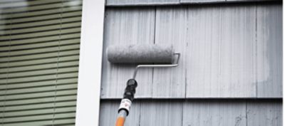 A roller applying a coating to a home's exterior.