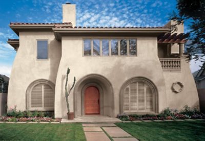 An exterior home with tan paint and a burnt orange painted door.