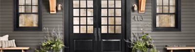 The entrance to a home with double front doors painted Triccorn Black and gray siding.