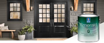 The exterior of a home with black doors with square glass windows and siding painted in dark gray. Product featured Emerald Urethane Trim Enamel.