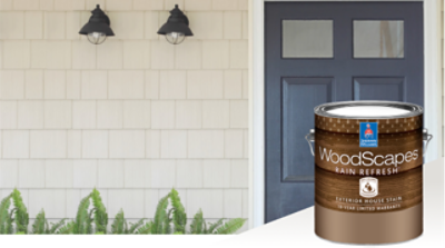 A home's exterior with a blue door and neutral siding with a can of Woodscapes in the foreground.