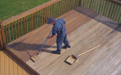 A man staining an outdoor patio deck.