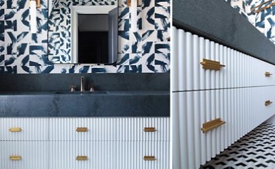 Full view and angled closeup of fluted white vanity with dark countertop and bold patterned wallpaper, dark blue tiled walk-in shower at right.