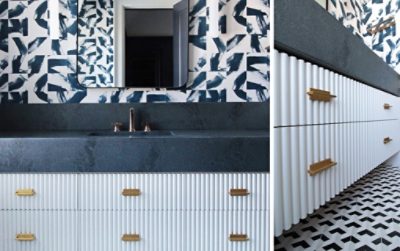 Full view and angled closeup of fluted white vanity with dark countertop and bold patterned wallpaper, dark blue tiled walk-in shower at right.